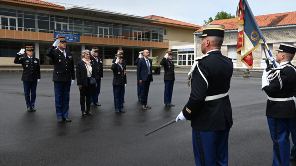 Un groupe de 8 généraux, officiers de gendarmerie en civil, saluant le drapeau et sa garde