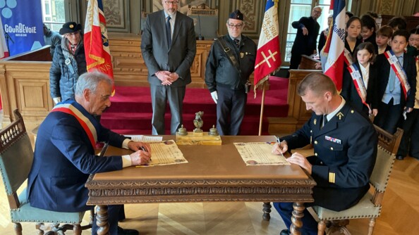 Signature du parrinage par le maire de Courbevois, à gauche, et le chef d’escadron, commandant l’EGM 16/1, à droite, assis de part et d'autre d'une table ancienne.