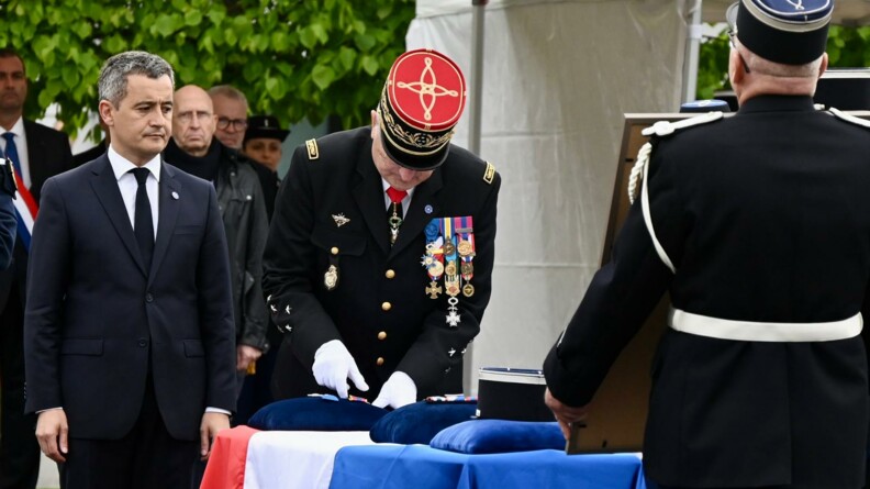 Le général d'armée Christian Rodriguez, Directeur général de la gendarmerie nationale, et le ministre de l'Intérieur, Gérald Darmanin, accrochent les médailles à des coussins bleus sur le cercueil recouvert du drapeau français.