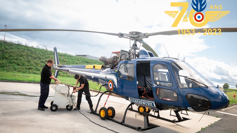 Photo présentant deux militaires de la gendarmerie effectuant des opérations sur un hélicoptère sur la piste présente à la sortie du hangar du CNaMAG.