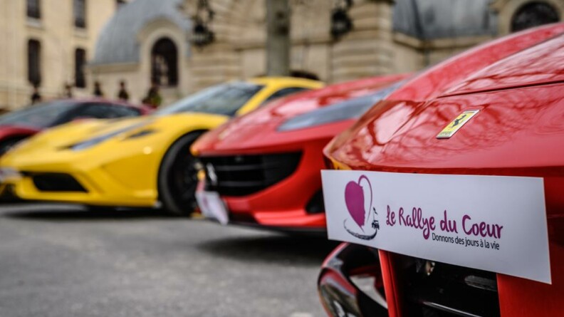 Quatre voiture de luxe, deux rouges, une jaune et une noire et rouge, avec la pancarte "Rallye du coeur, donnons des jours à la vie"