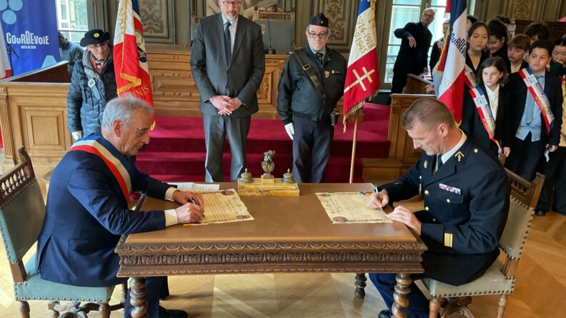 Signature du parrinage par le maire de Courbevois, à gauche, et le chef d’escadron, commandant l’EGM 16/1, à droite, assis de part et d'autre d'une table ancienne.