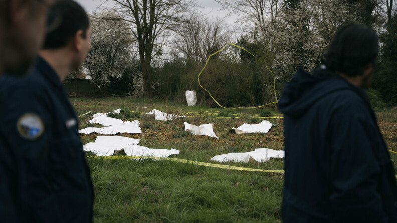 Zoom sur une zone balisée avec une dizaine de draps mortuaires symbolisant les corps.