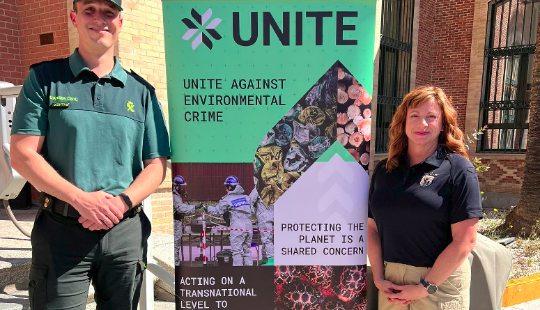 Un personnel de la Guardia civil et une représentante des services de protection de la biodiversité aux Etats-Unis posent devant une affiche promouvant le projet UNITE.