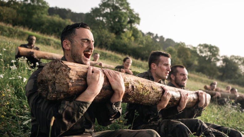 Trois militaires masculins effectuant des abdominaux avec un tronc d'arbre.