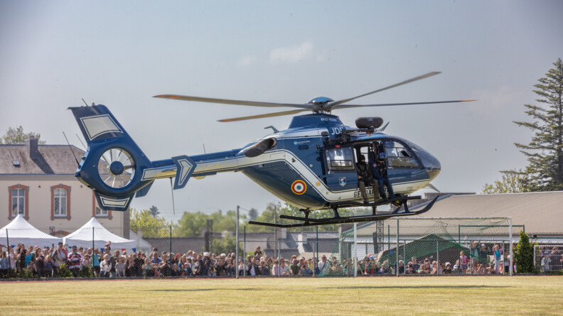 Un hélicoptère des forces aériennes décolle sur un terrain du football.