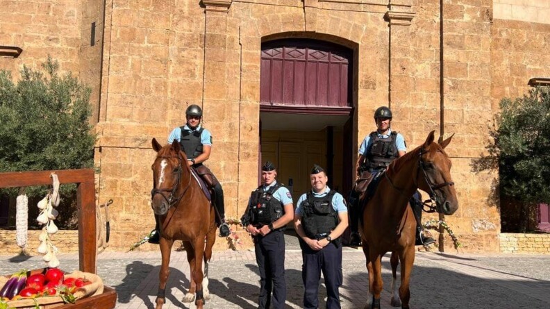 Devant une église et à cheval, deux gendarmes accompagnés de deux autres gendarmes à pied, assurent la sécurisation de la messe de l'assomption.