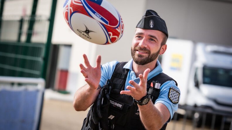 Un gendarme souriantn mains ouvertes, recevant un ballon de la coupe du monde siglé Chili