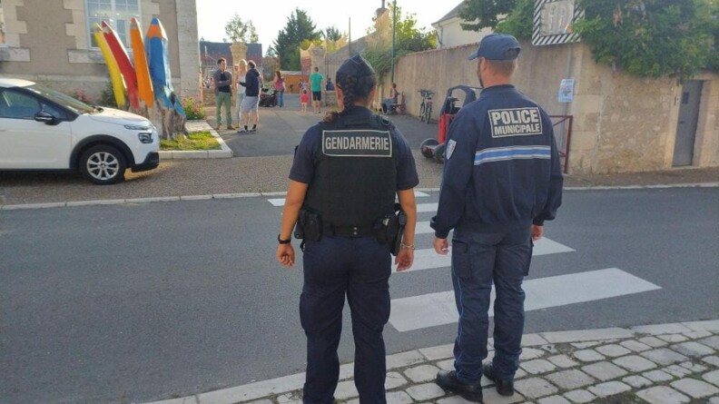 Une gendarme et un policier municipale devant une école.