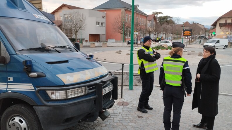 Deux gendarmes devant un irisbus s'entretiennent avec une femme au bord d'un rond point