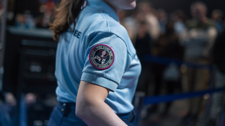 On voit de biais une femme gendarme en tenue en train d'avancer. Sur le manche droite de son polo bleu clair est visible l'écusson de la gendarmerie nationale à l'éffigie de la Paris Games Week