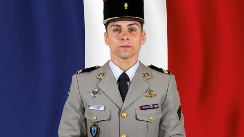 Portrait du sergent Baptiste Gauchot en vareuse militaire et képi, devant le drapeau français.