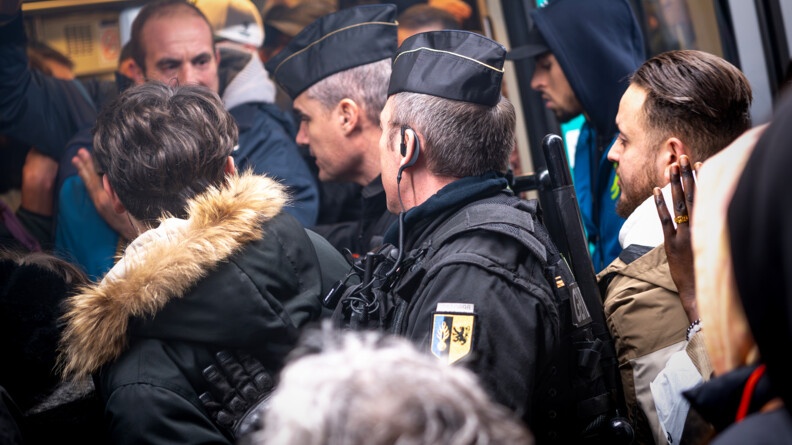 Gendarmes régulant les personnes à l'entrée d'une rame de métro pour permettre à la porte de se fermer.