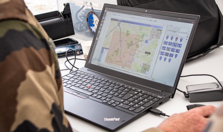 Un gendarme réalisant une infographie sur son ordinateur portable.