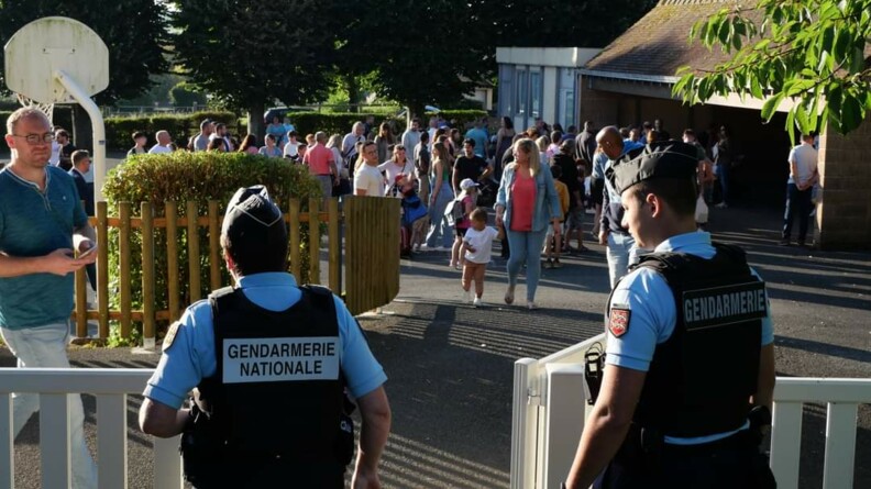 Deux gendarmes devant une école primaire abordent un responsable éducatif.