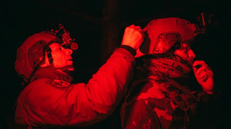 Deux militaires ajustent un casque en vision nocturne. Photo en rouge et noir