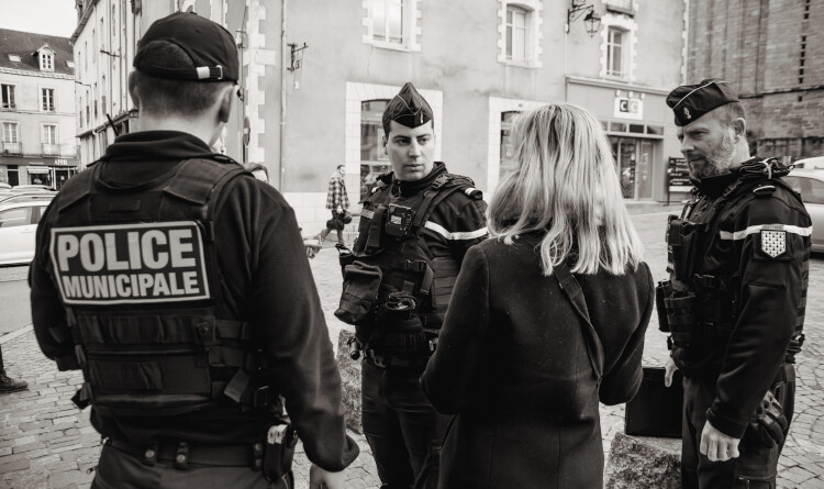 2 gendarmes et un policier discutant avec une femme de dos.