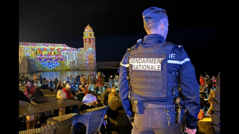 Le soir du nouvel an, un gendarme de dos, de nuit, surveille une zone très fréquentée de la ville.