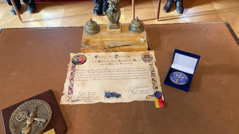 Convention de parrainage signée et médailles de l'association des villes marraines et du Groupement blindé de gendarmerie mobile.