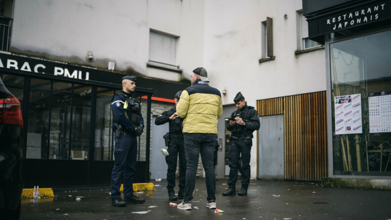 Trois gendarmes procèdent au contrôle d'un piéton au pied de bâtiments