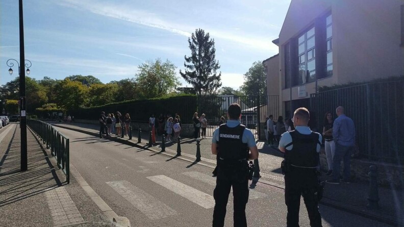 Deux gendarmes devant un établissement scolaire.