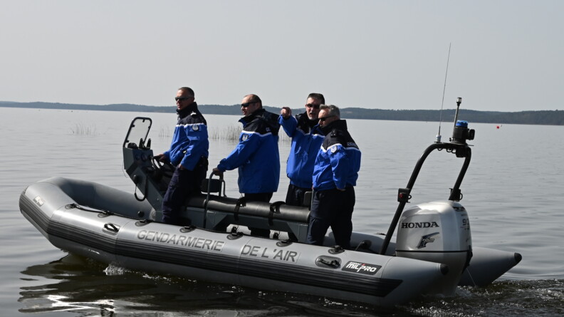 Quatre militaires de la gendarmerie de l'Air en patrouille à bord d'un zodiac sur un plan d'eau.