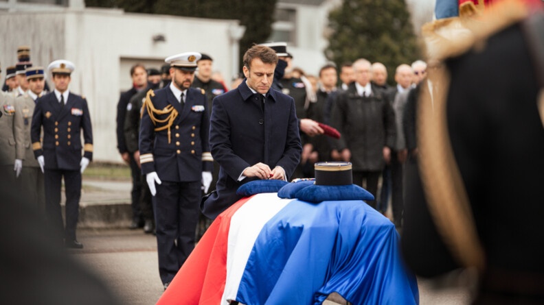 Le président de la République, Emmanuel Macron, dépose les insignes de Chevalier de la Légion d'Honneur sur le cercueil du major Arnaud Blanc, recouvert du drapeau français.