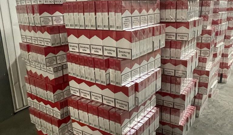 Plusieurs piles de cartouches de cigarettes dans un hangar.