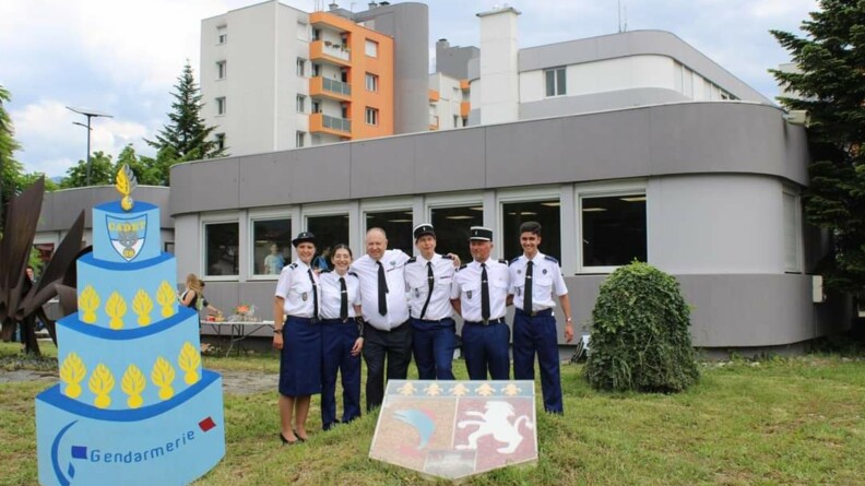 Les gendarmes intervenant dans le cadre de l'association posent près d'une pancarte représentant un gâteau d'anniversaire.