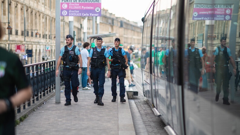 Une patrouille de trois gendarmes, vus de face, sur les quais du tramway bordelais. Sur la droite de la photo, le tram qui s'en va.