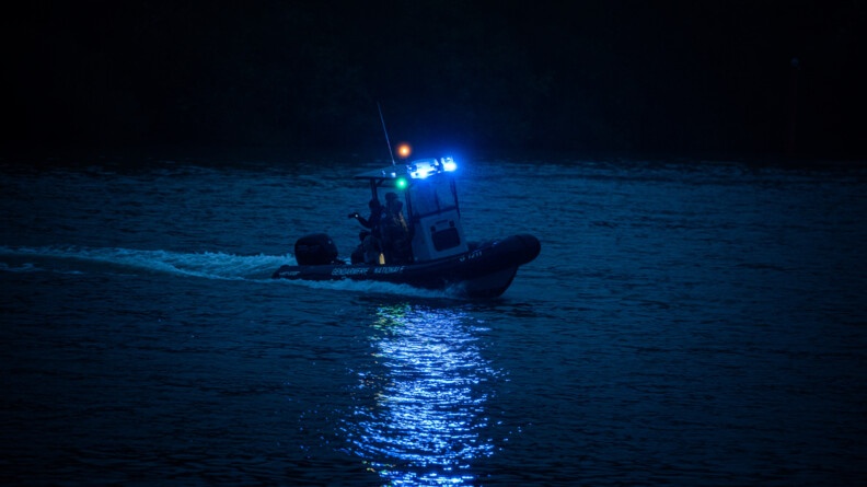 Au centre de l'image, un zodiac de la gendarmerie des voies navigables, navigue sur la Seine pendant la nuit.