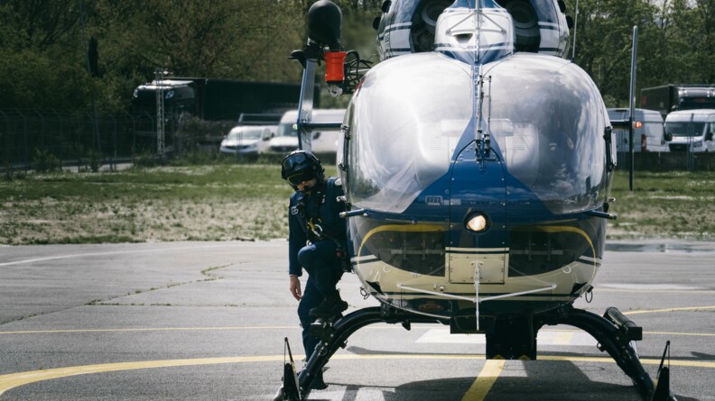 Un pilote de la gendarmerie descend de l'hélicoptère posé au sol.