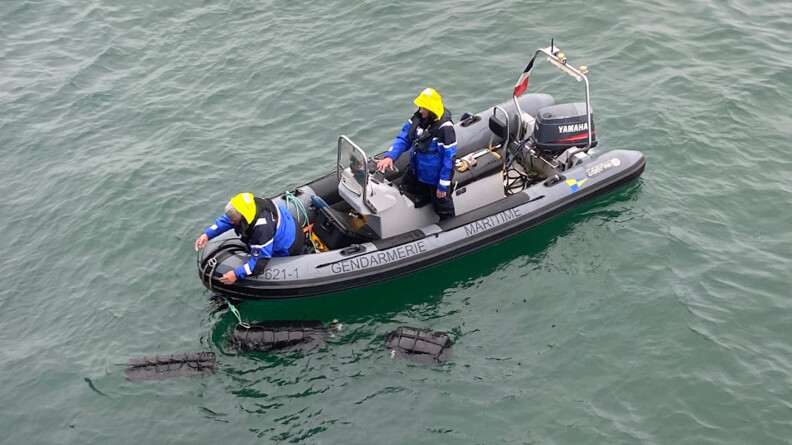 Deux gendarmes de la gendarmerie maritime à bord d'un zodiaque, récupèrent trois ballots de cocaïne conditionnée, dissimulés dans la coque du cargo Nord Capella, le 16 février dans le port de Brest.