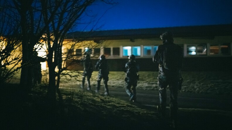 Quatre militaires en colonne par un se déplacent de nuit vers un bâtiment