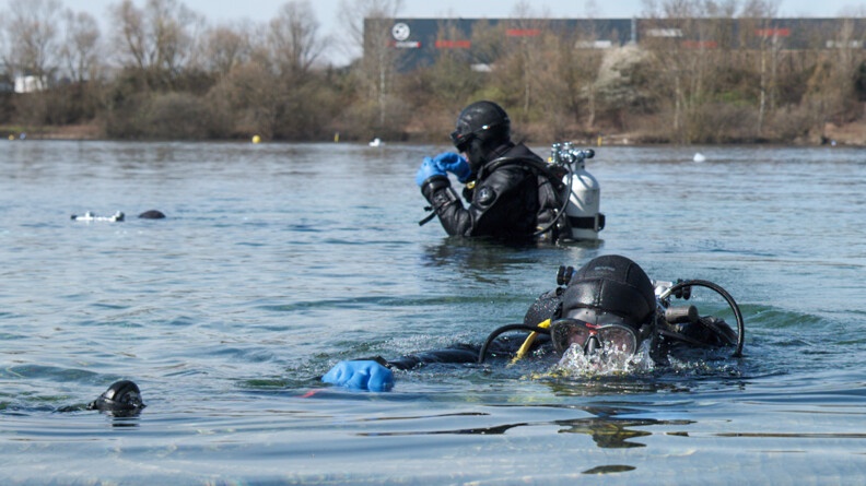 Deux plongeurs dans l'eau débutent l'exercice de recherche de véhicule.
