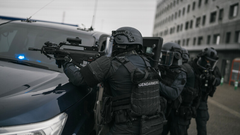 Photo d'une colonne de gendarmes du PSPG qui s'appuient et se protègent derrière leur véhicule.