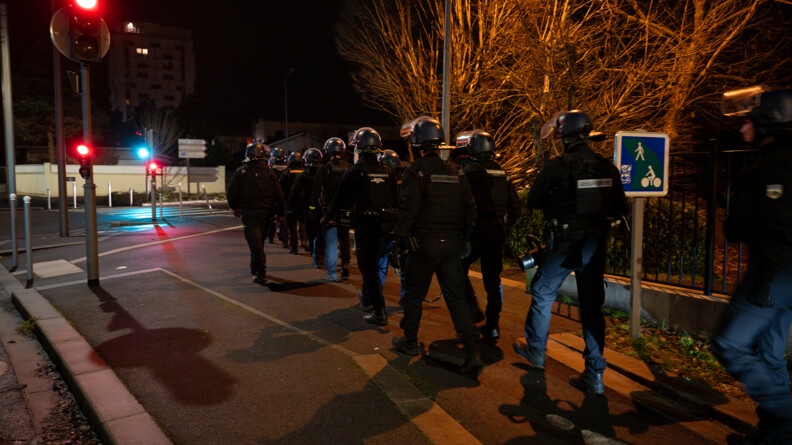 Il fait nuit, un groupe d'une vingtaine de gendarmes marchent dans la rue en tenue d'intervention.