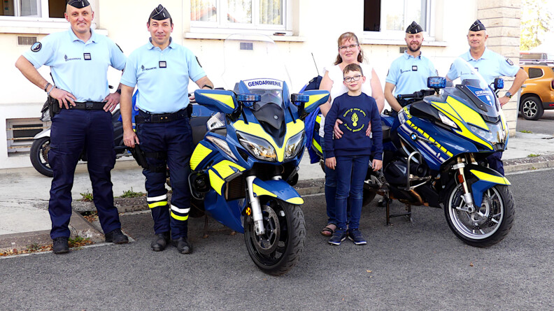 Tom et sa maman posent avec quatre gendarmes et deux motos de la gendarmerie.