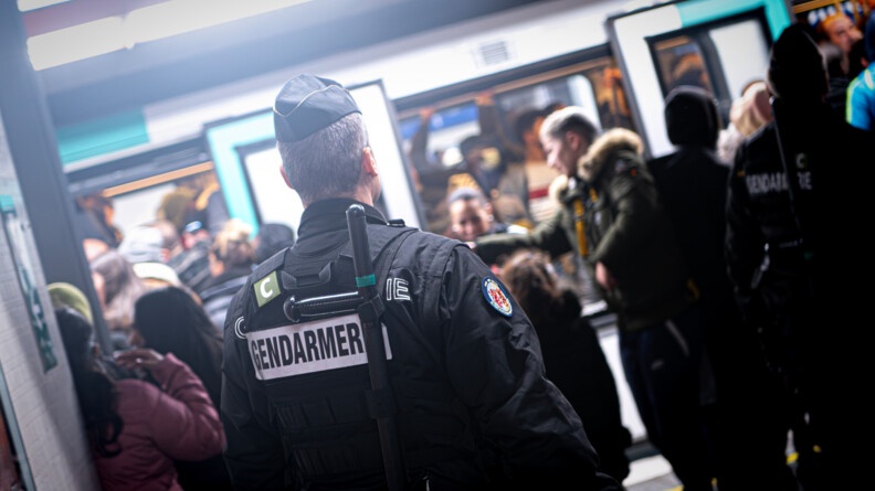 Gendarme de dos devant une rame de métro.