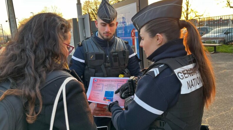 Deux gendarmes discutent avec une femme autour d'un flyer expliquant le harcèlement dans les transports