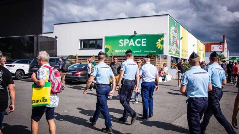 Conq gendarmes marchant vers la gauche de l'image devant le SPACE 2023. De nombreux visiteurs à l'extérieur