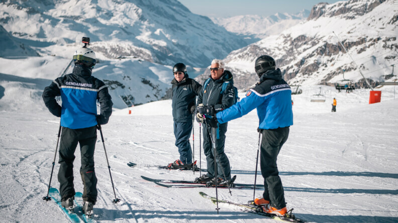Deux gendarmes à ski entrain d'échanger avec des skieurs.