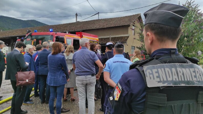 Autorités locales, journalistes et forces de gendarmerie rassemblés à proximité d'un camion des sapeurs-pompiers.