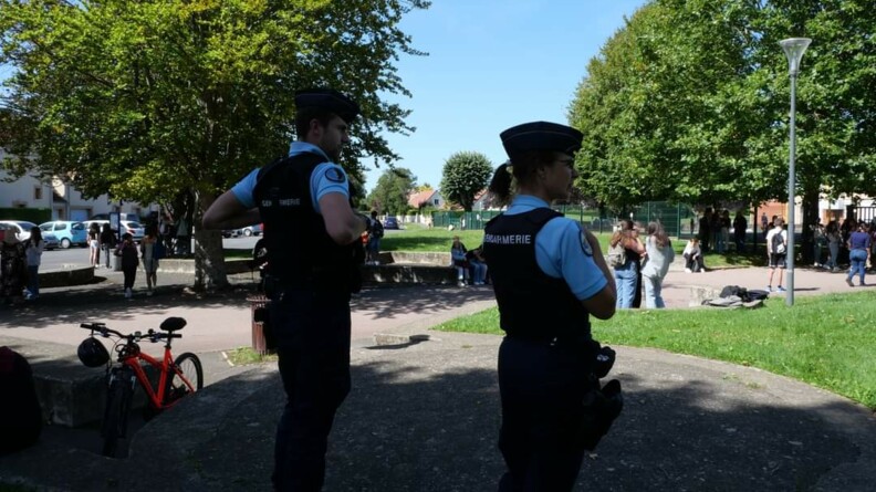 Deux gendarmes observant les jeunes aux abords d'un établissement scolaire.