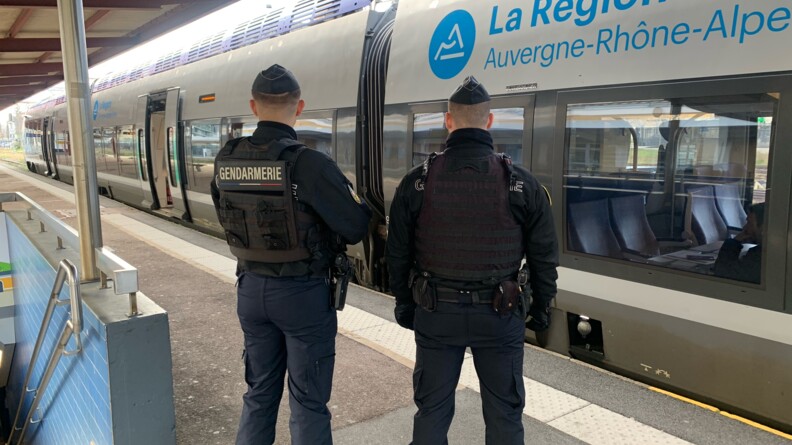 Deux gendarmes mobiles de dos sur le quai devant un train de la région AUvergne Rhône Alpes