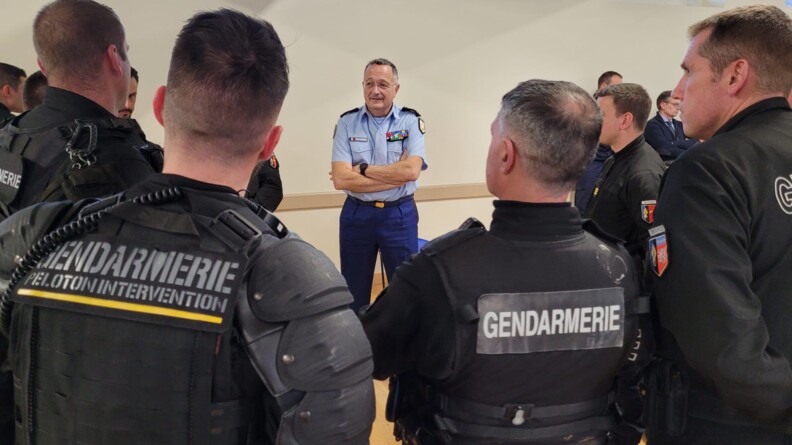 Plusieurs gendarmes en tenue de maintien de l'ordre vus de dos. Face à eux le directeur général de la gendarmerie.