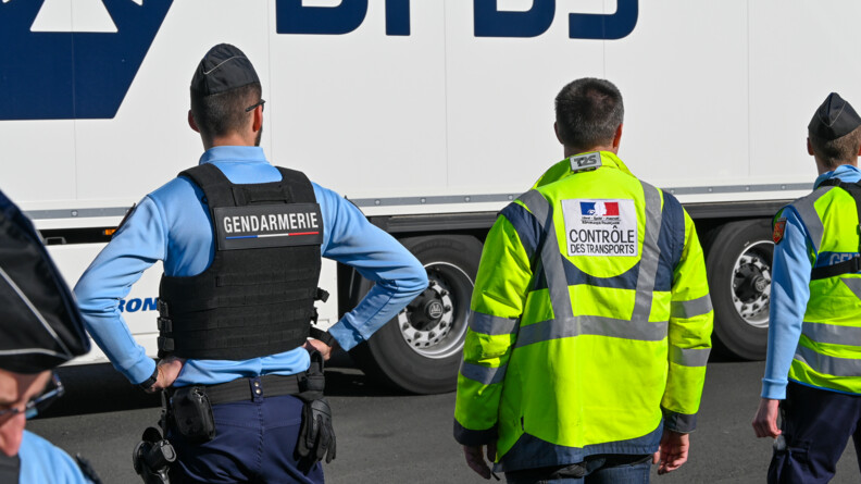 Un gendarme et un contrôleur des transports terrestres de dos lors d'un contrôle.