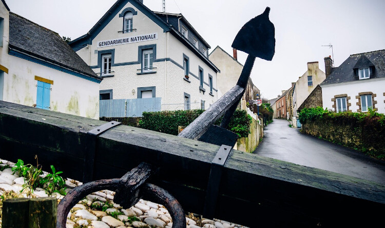 Vue de la brigade de gendarmerie de l'Île de Groix, image en contre-plongée avec au premier plan une ancre de bateau en bois noir