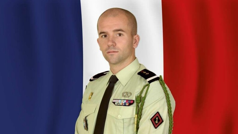 Portrait de l'adjudant Nicolas Latourte en tenue devant le drapeau français.