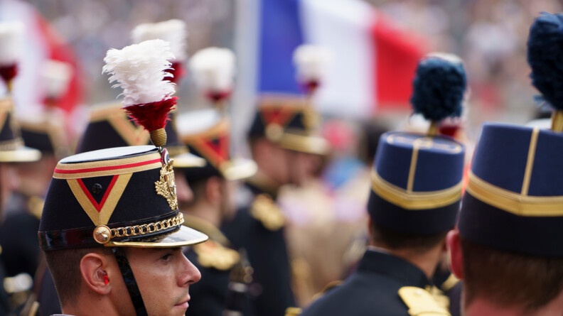 En uniforme de cérémonie, à gauche un garde républicain et à droite un élève de l'EOGN. En fond, un magnifique drapeau français qui flotte au vent.